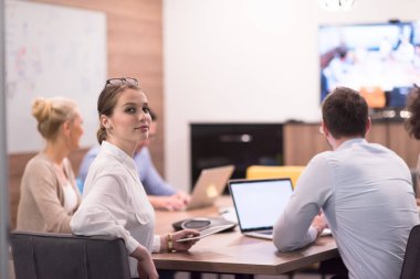 Bir grup genç iş adamı modern ofis binasında iş planlarını tartışıyor