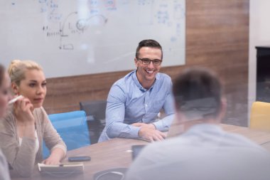 Bir grup genç iş adamı modern ofis binasında iş planlarını tartışıyor