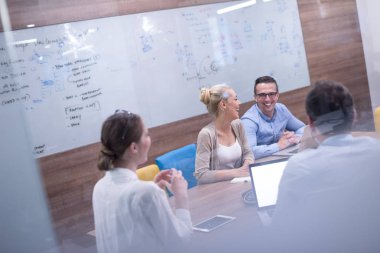 Bir grup genç iş adamı modern ofis binasında iş planlarını tartışıyor