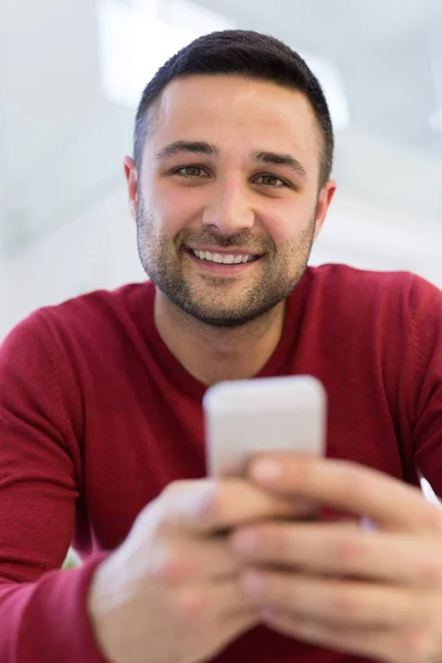 Jonge man met behulp van een mobiele telefoon thuis — Stockfoto