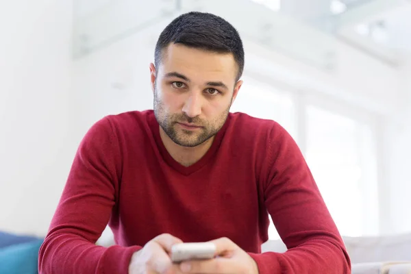 Junger Mann mit Handy zu Hause — Stockfoto