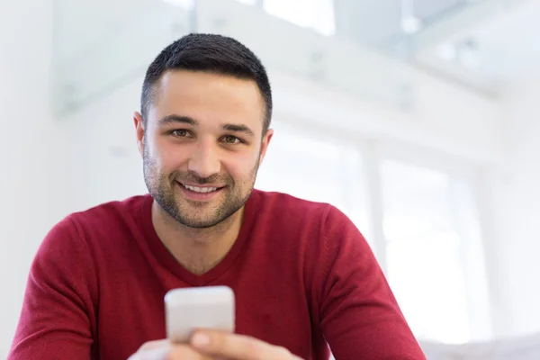 Jonge man met behulp van een mobiele telefoon thuis — Stockfoto