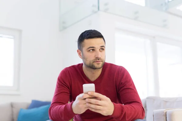 Jonge man met behulp van een mobiele telefoon thuis — Stockfoto