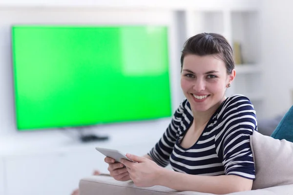 Женщина на диване с помощью планшетного компьютера — стоковое фото