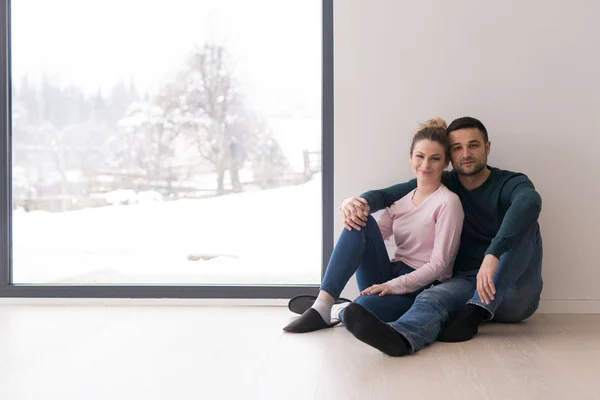 Jovem casal sentado no chão perto da janela em casa — Fotografia de Stock