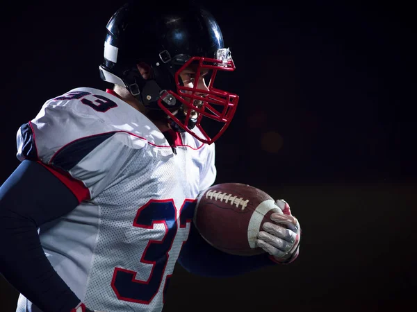 American football speler bal te houden terwijl u op een veld uitvoert — Stockfoto