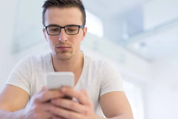 Jonge man met behulp van een mobiele telefoon thuis — Stockfoto