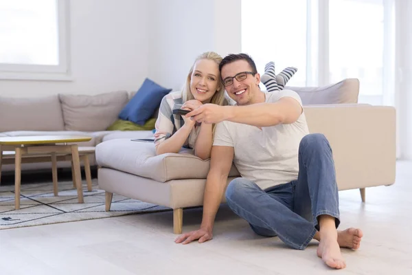 Jovem casal no sofá assistindo televisão — Fotografia de Stock