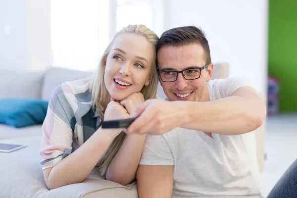 Pareja joven en el sofá viendo la televisión —  Fotos de Stock