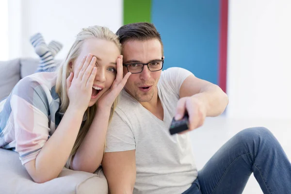 Pareja joven en el sofá viendo la televisión —  Fotos de Stock