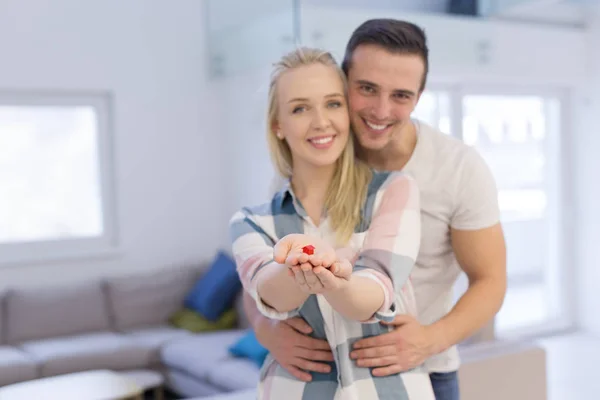 Casal mostrando pequena casa vermelha nas mãos — Fotografia de Stock