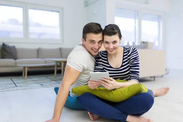 Unga par med digital tablett på golvet — Stockfoto