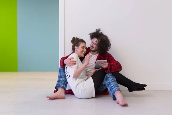 Unga par med digital tablett på golvet — Stockfoto