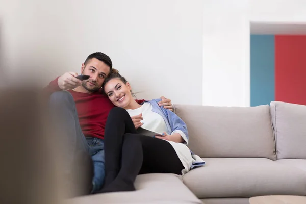 Молода пара на дивані дивиться телевізор — стокове фото