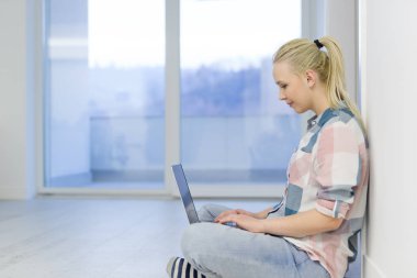 yere dizüstü bilgisayar kullanan genç kadın