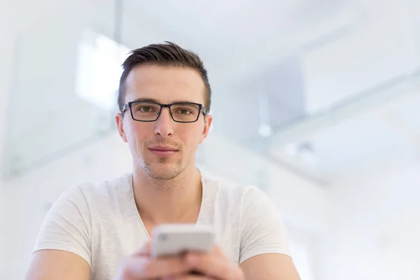 Jeune homme utilisant un téléphone portable à la maison — Photo