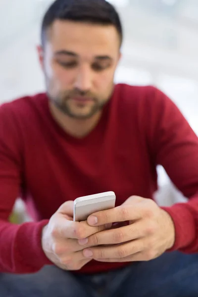 Jonge man met behulp van een mobiele telefoon thuis — Stockfoto