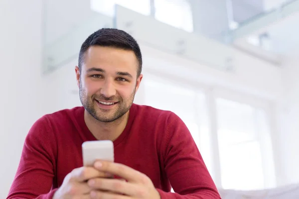 Giovane utilizzando un telefono cellulare a casa — Foto Stock