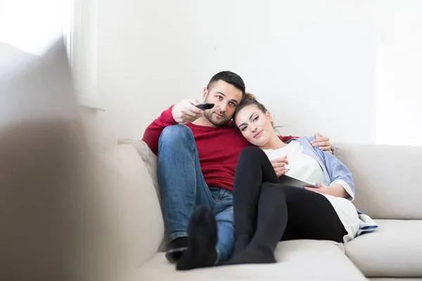 Jovem casal no sofá assistindo televisão — Fotografia de Stock