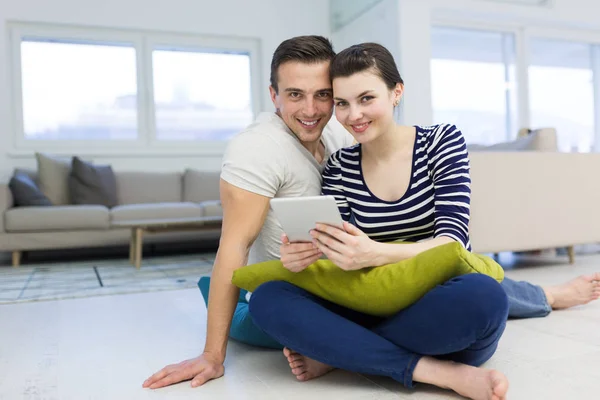 Mladý pár pomocí digitálních tabletu na podlaze — Stock fotografie