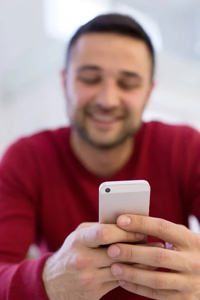 Jonge man met behulp van een mobiele telefoon thuis — Stockfoto