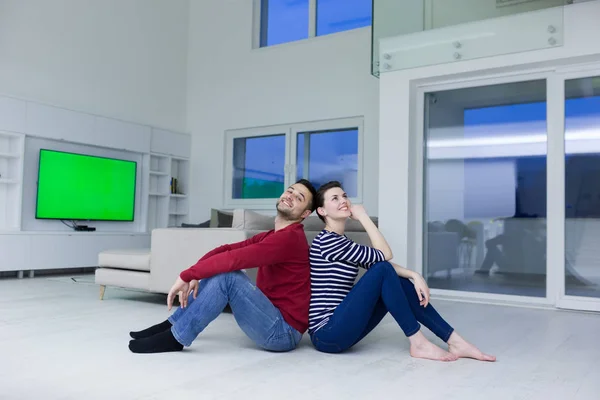 Young couple sitting with back to each other on floor — Stock Photo, Image