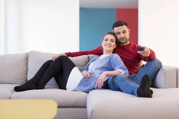 Jovem casal no sofá assistindo televisão — Fotografia de Stock