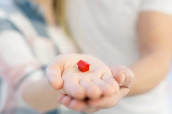 Pareja mostrando pequeña casa roja en las manos —  Fotos de Stock