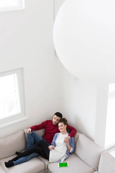 Pareja joven en el sofá viendo la televisión —  Fotos de Stock