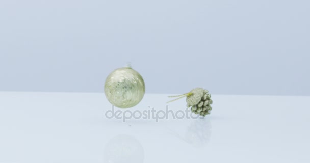 boules de Noël rouges et dorées et décoration tombent et rebondissent au ralenti sur fond blanc réfléchissant  
