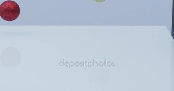 boules de Noël rouges et dorées et décoration tombent et rebondissent au ralenti sur fond blanc réfléchissant  