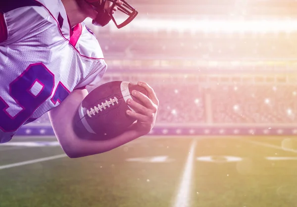 Amerikansk fotbollsspelare håller bollen medan du kör på fältet — Stockfoto