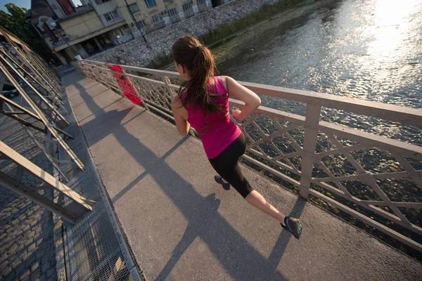 Donna che corre attraverso il ponte al mattino di sole — Foto Stock