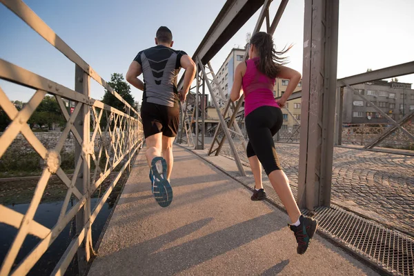 Fiatal pár, jogging, át a hídon a városban — Stock Fotó