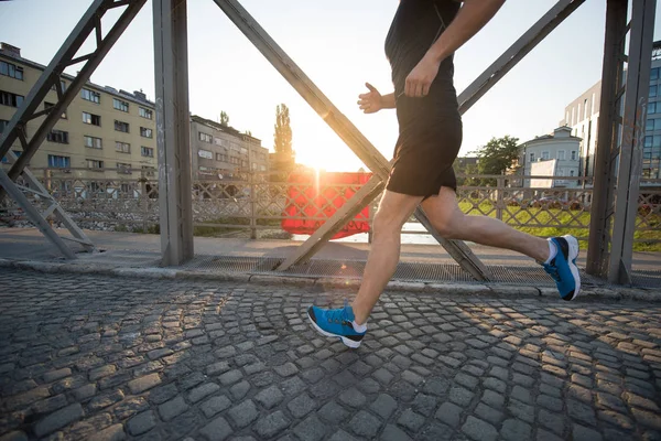 Człowiek, jogging przez most w słoneczny poranek — Zdjęcie stockowe