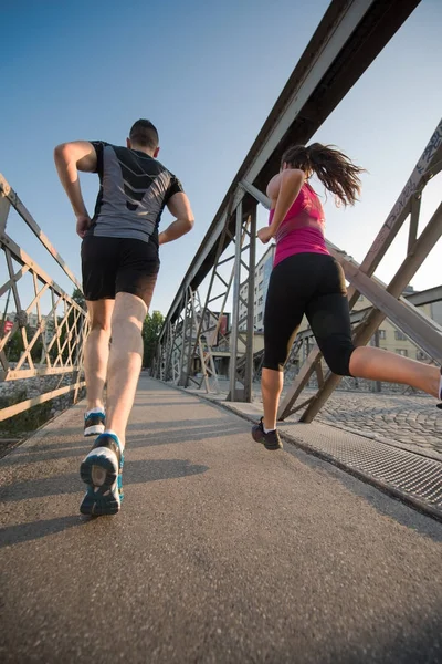 年轻夫妇在城市的桥上慢跑 — 图库照片