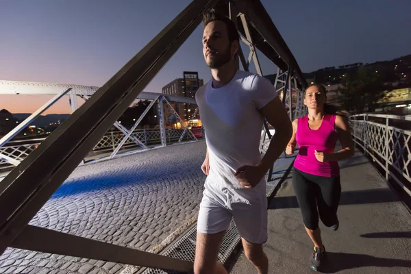 Couple jogging à travers le pont dans la ville — Photo