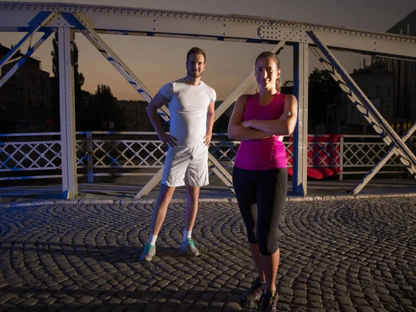 Portret van paar joggen over de brug in de stad — Stockfoto