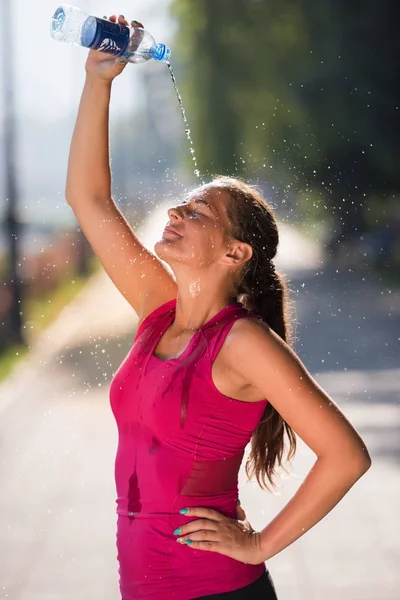 Mujer vertiendo agua de la botella en su cabeza — Foto de Stock