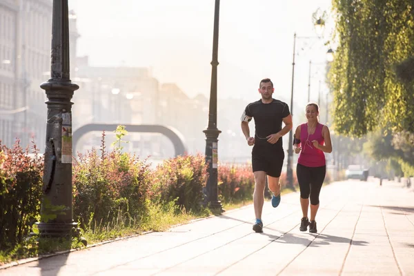 Jeune couple jogging dans la ville — Photo