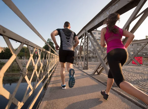 Młoda para joggingu przez most w mieście — Zdjęcie stockowe