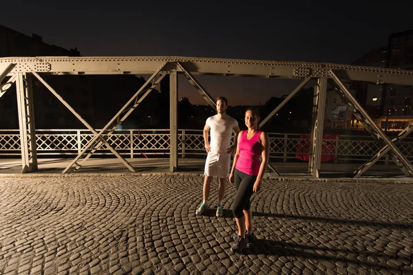 Couple jogging across the bridge in the city — Stock Photo, Image