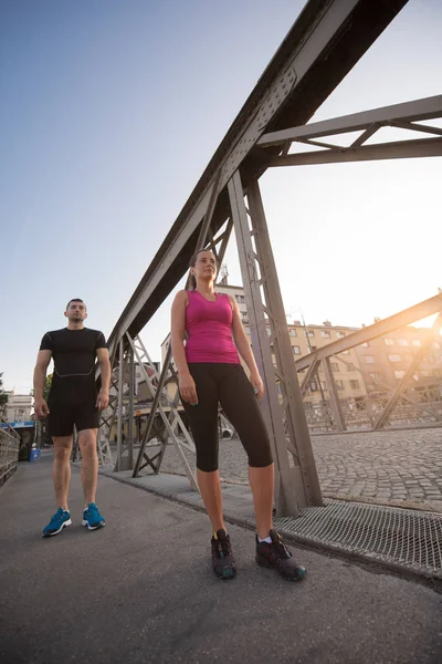 Ungt par jogging över bron i staden — Stockfoto