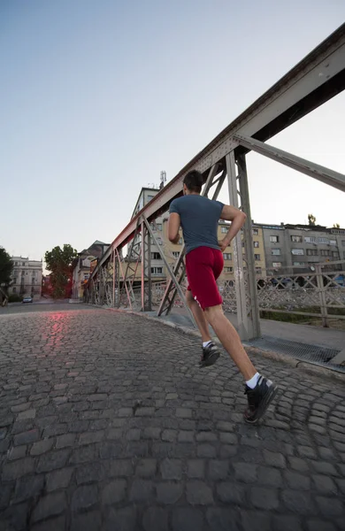 Hombre corriendo a través del puente en la mañana soleada —  Fotos de Stock