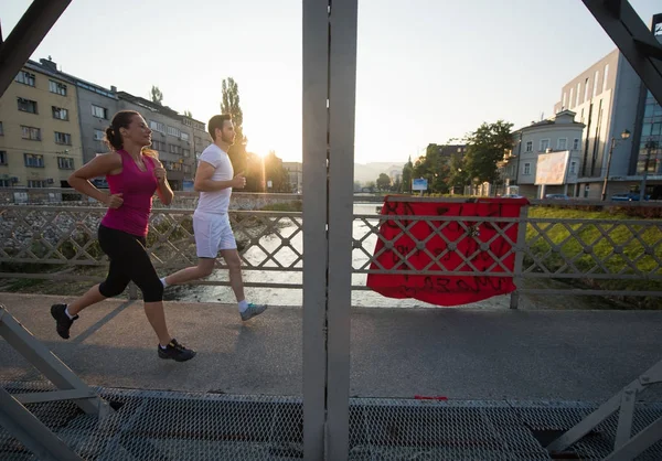 Junges Paar joggt in der Stadt über die Brücke — Stockfoto