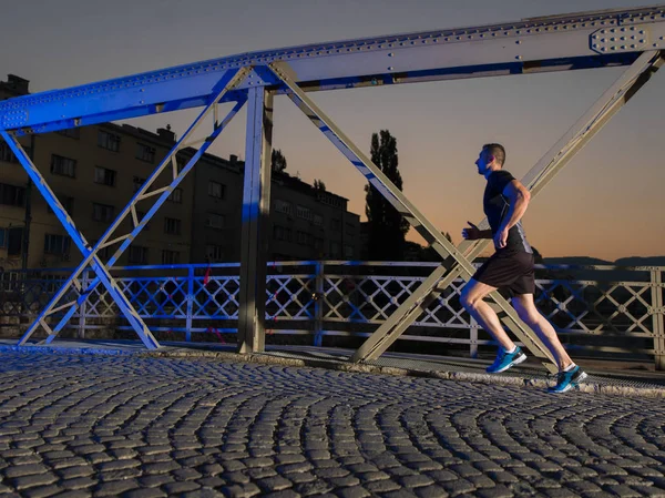 Homme jogging à travers le pont dans la ville — Photo