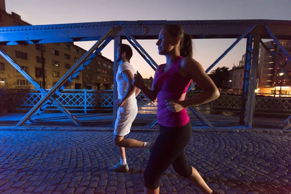 Couple jogging à travers le pont dans la ville — Photo