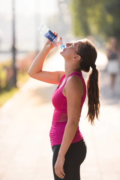 Frau trinkt nach Joggen Wasser aus Flasche — Stockfoto