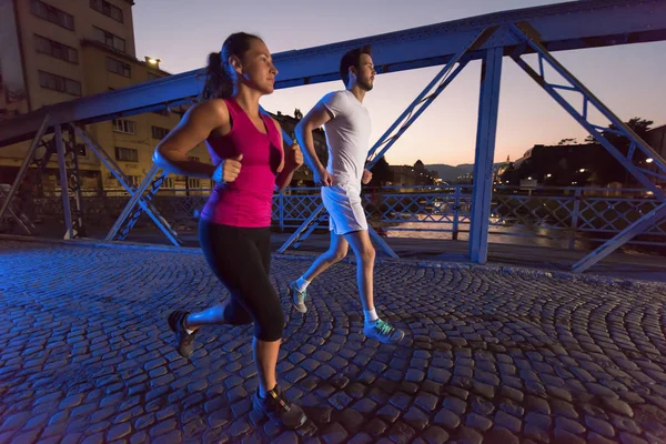 Couple jogging à travers le pont dans la ville — Photo