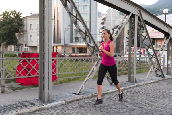 Donna che corre attraverso il ponte al mattino di sole — Foto Stock